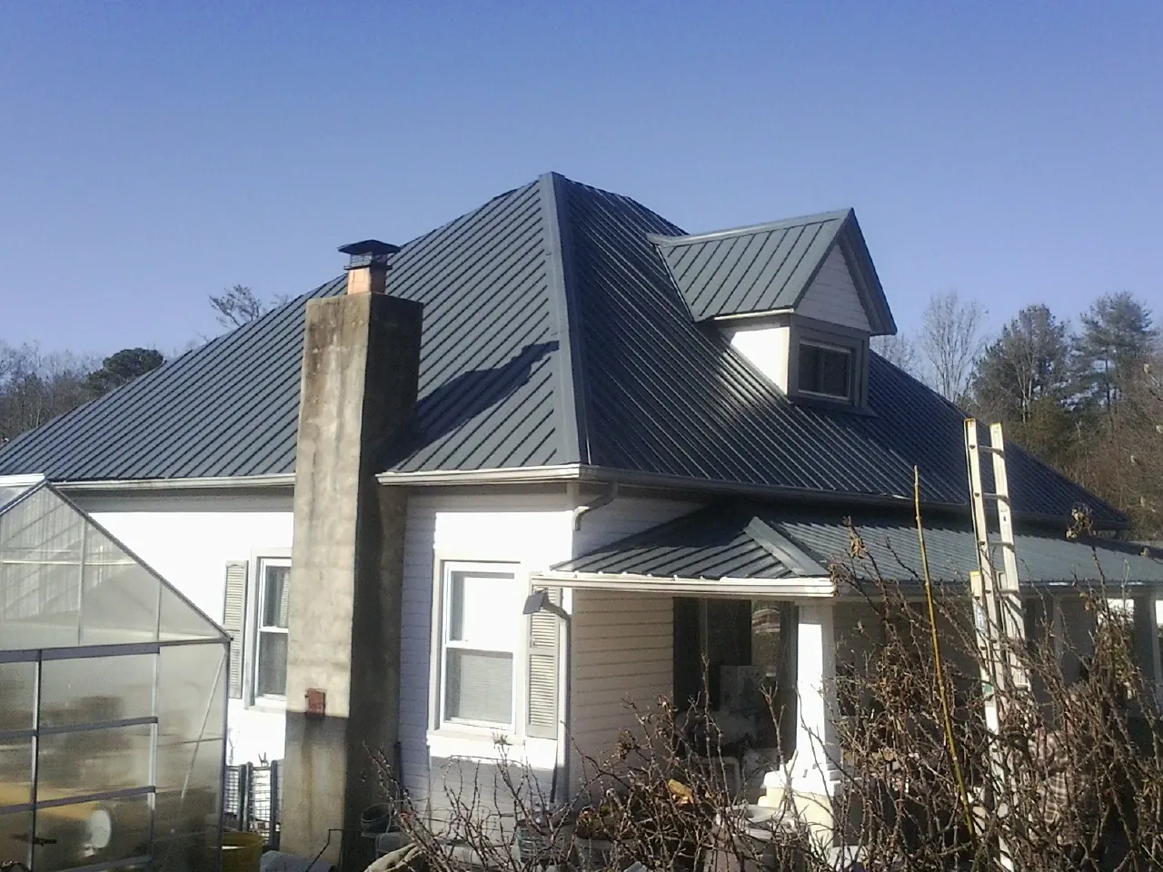 Dark blue standing seam metal roof on a white farmhouse with dormer — Slate & Tile Roof Repair by Roofing Brothers in Bovill