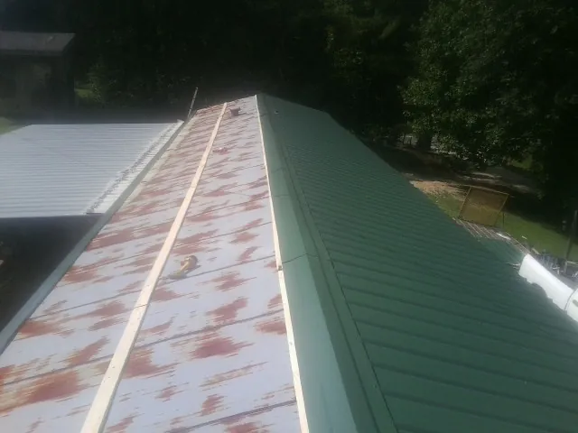 Old rusted panels beside newly installed green metal roofing — Wind Damage Roof Repair by Roofing Brothers in Bovill
