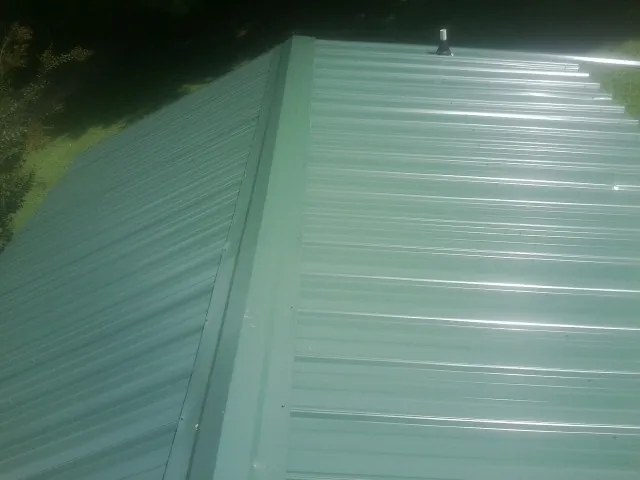 New green metal panels meeting at the ridge of a roof — Flat Roof Repair work by our crew in Bovill