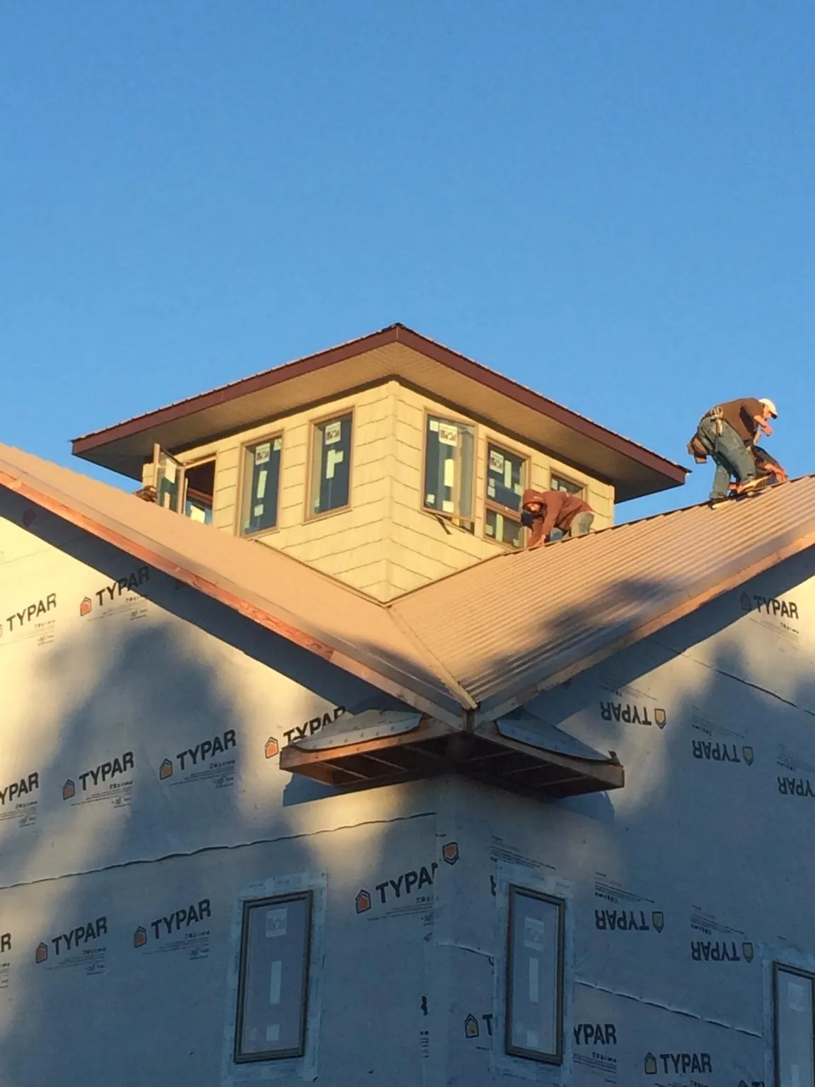 Roofers working around a rooftop cupola on a new metal roof at sunset — Roof Waterproofing in Bovill by Roofing Brothers